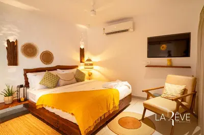 a bedroom with a bed and a chair and a tv at LA RÊVE The Beach Villa in Malappuram