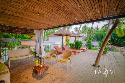 an outdoor patio with chairs and tables and umbrellas at LA RÊVE The Beach Villa in Malappuram