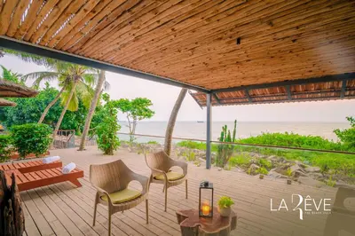 a deck with chairs and a bench and the beach at LA RÊVE The Beach Villa in Malappuram