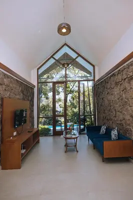 a living room with a blue couch and a stone wall at Elixir Woods Luxury Resort And Spa, Munnar in Munnar