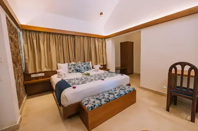 a bedroom with a bed with a chair and a window at Elixir Woods Luxury Resort And Spa, Munnar in Munnar