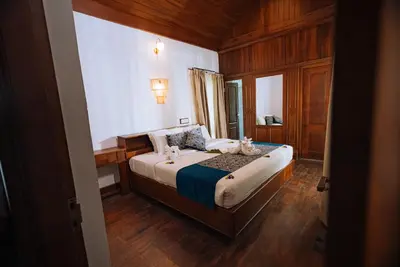 a bedroom with a bed in a room with wooden floors at Elixir Woods Luxury Resort And Spa, Munnar in Munnar