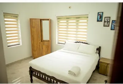 a bedroom with a bed with white sheets and pillows at Chills homestay in Kalpetta