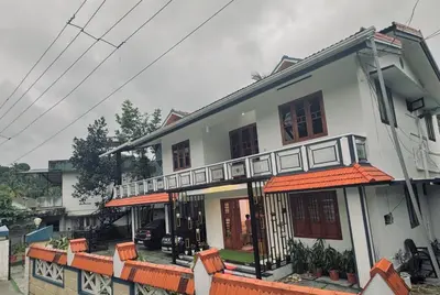 a white house with orange awnings on it at Chills homestay in Kalpetta