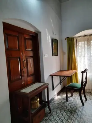 a room with a wooden door and a table and a chair at Heritage Home, Hampe's in Mysore