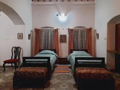 a room with two beds and two chairs at Heritage Home, Hampe's in Mysore
