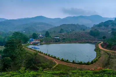 a lake in a valley with mountains in the background at jungle view resort in Mananthavady