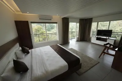 a bedroom with a bed and a balcony with a desk at jungle view resort in Mananthavady