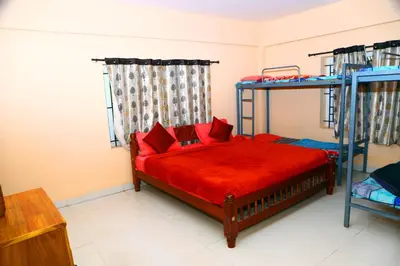 a bedroom with two bunk beds with red sheets at J J HOMES in Ooty
