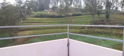 a balcony with a view of a field at J J HOMES in Ooty