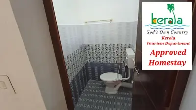 a bathroom with a toilet and a sign on the door at Space villa Homestay in Irimbranallūr