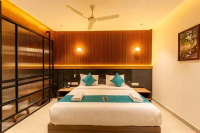 a bedroom with a large bed with blue pillows at Hotel Stay Bella Kozhikode in Kozhikode