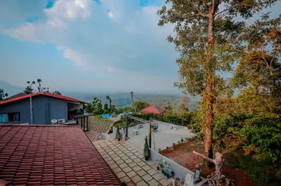 a house with a brick walkway next to a tree at The Odyssey Coorg in Madikeri