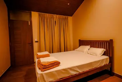 a bedroom with a bed with white sheets and a window at The Odyssey Coorg in Madikeri