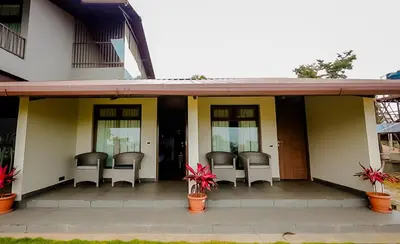 a porch of a house with chairs and plants at The Odyssey Coorg in Madikeri