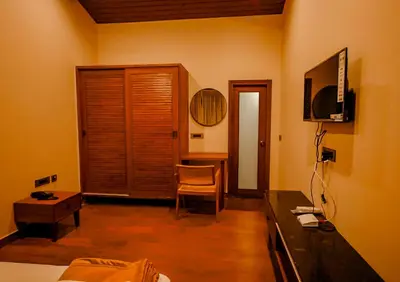 a room with a bed and a desk and a television at The Odyssey Coorg in Madikeri