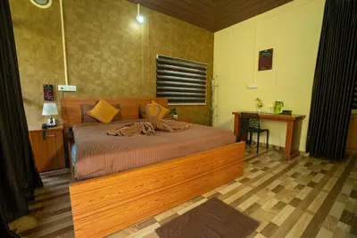 a bedroom with a bed and a desk and a table sidx sidx sidx at Hill Valley Farm House in Nelliyampathy
