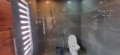 a bathroom with a white toilet in a tiled wall at Empire Single Bedroom Villa with Common Pool in Meenangadi