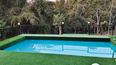 a swimming pool in the grass with a fence at Greens Vista Homestay Wayanad Near Natural Stream and Pool in Panamaram