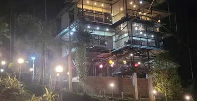 a tall building with a balcony at night at Greens Vista Homestay Wayanad Near Natural Stream and Pool in Panamaram