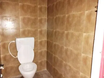 a bathroom with a toilet and a tiled wall at SHI Triveni 1BHK at Coimbatore Outskirts in Irugūr