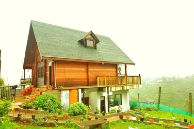a small house with a balcony on top of it at Joy Eco Woodhouse - 3 Bhk House in Ooty
