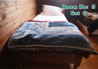 a bed with a blue blanket on top of it at Joy Eco Woodhouse - 3 Bhk House in Ooty