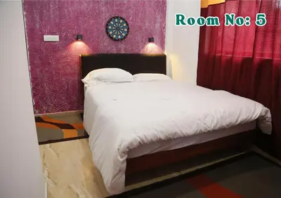 a bedroom with a white bed with a red wall at Joy Eco Woodhouse - 3 Bhk House in Ooty