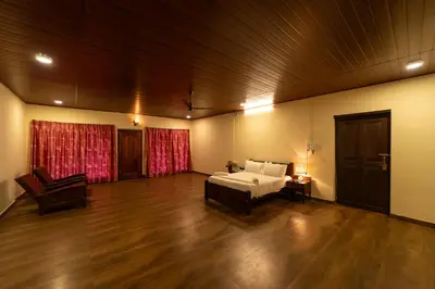 a large room with a bed and a wooden floor at Harris Holiday Inn in Vālpārai