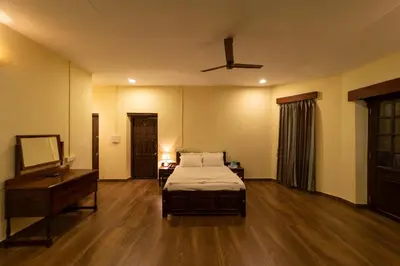 a bedroom with a bed and a desk and a ceiling fan at Harris Holiday Inn in Vālpārai