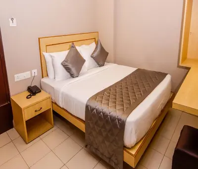 a bedroom with a large bed with a nightstand and a bed sidx sidx sidx at Hotel Vinayaga Tiruppur in Tiruppūr