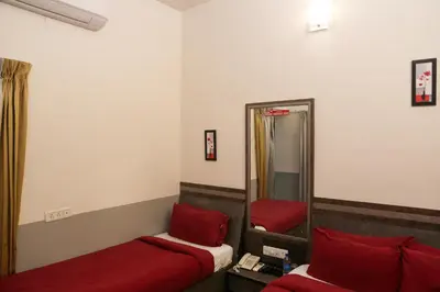 a bedroom with two beds and a mirror at Hotel Sapthagiri Nest in Coimbatore