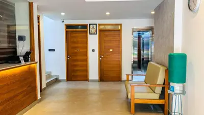 a hallway with wooden doors and a chair in a room at Rose Garden at Rajagiri Hospital in Ernakulam