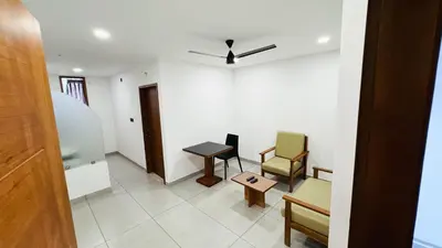 a living room with two chairs and a table at Rose Garden at Rajagiri Hospital in Ernakulam