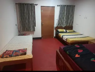 a room with three beds and a door with curtains at Vattavada Jungle Resort in Munnar