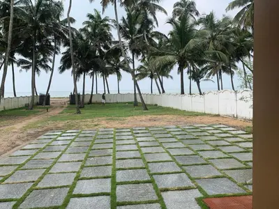 a stone pathway with palm trees in the background at Casa Ganesha beach villa in Irimbranallūr