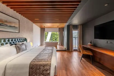 a bedroom with a large bed and a flat screen tv at Sterling Athirappilly in Athirappilly