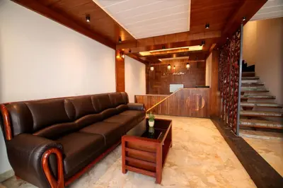 a living room with a leather couch and a staircase at ARIAT AVENUE in Wayanad
