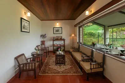 a living room with chairs and a table and a window at Emerald by Nature Resorts and Stays in Ooty