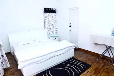 a white bedroom with a white bed and a black rug at HAILSTONE HOME STAY in Ooty