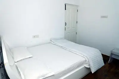 a white room with a bed with white sheets at HAILSTONE HOME STAY in Ooty