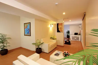 a living room with white furniture and plants at HOTEL SRIVATSA REGENCY in Pudunagaram