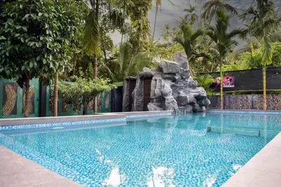 a swimming pool with a waterfall in a resort at Farm Fort Resort in Kozhikode