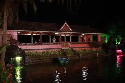 a house with lights on the water at night at Farm Fort Resort in Kozhikode