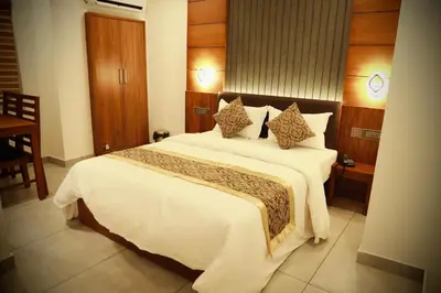 a bedroom with a large bed with white sheets and pillows at Silverstone Inn in Nedumbassery