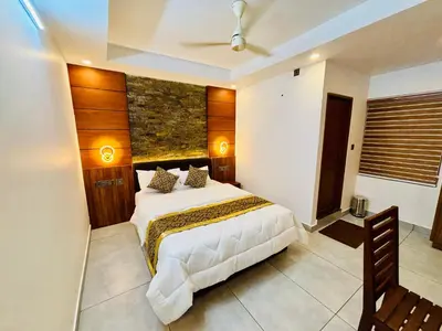 a bedroom with a white bed and a stone wall at Silverstone Inn in Nedumbassery