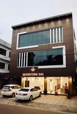 two cars parked in a parking lot in front of a building at Silverstone Inn in Nedumbassery