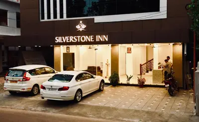 two cars parked in a parking lot in front of a store at Silverstone Inn in Nedumbassery