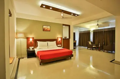 a bedroom with a red bed and a living room at Harbour Hotels in Pallipuram