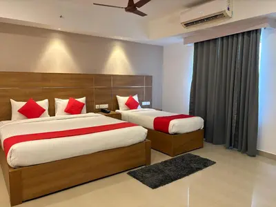 a bedroom with two beds with red pillows at Hotel Mangala Temple View in Guruvāyūr